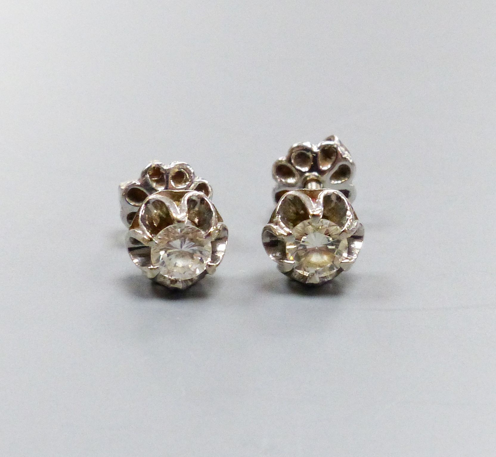 A pair of white metal and solitaire diamond set ear studs, each stone approx. 0.20ct, gross weight 2.4 grams.